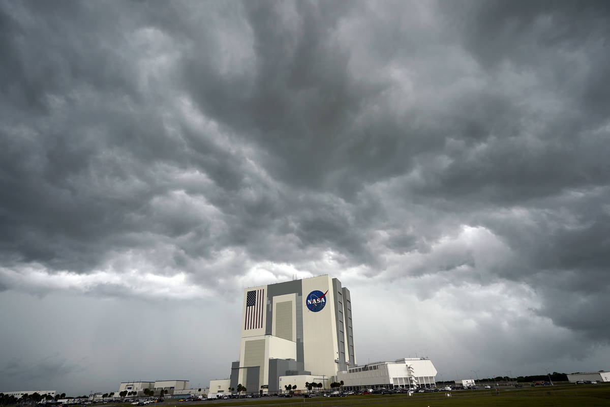 Storm clouds pass over the Vehicle Assembly Building as the SpaceX Falcon 9, with the Crew Drag ...