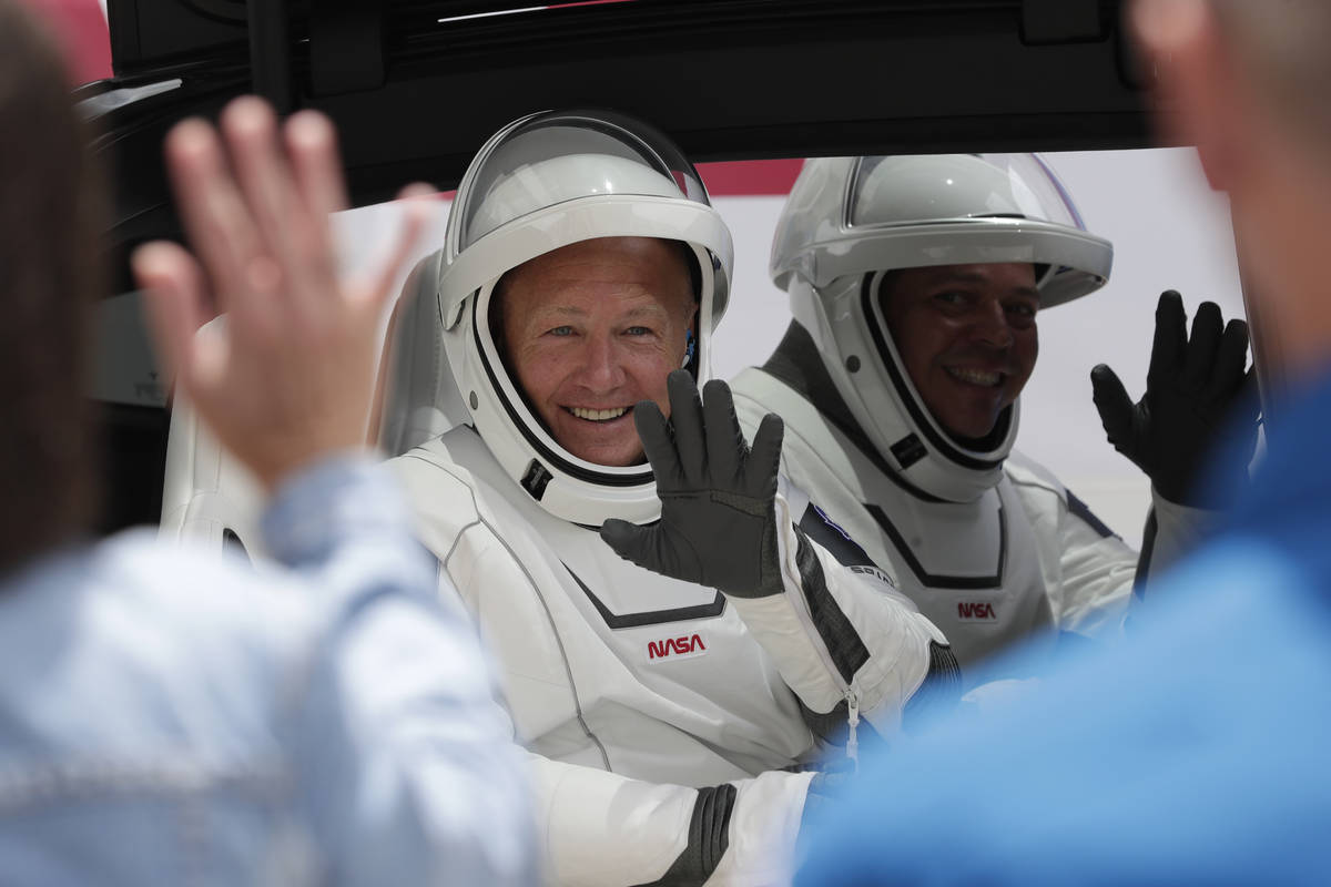 NASA astronauts Douglas Hurley, left, and Robert Behnken ride a Tesla SUV from the Neil A. Arms ...