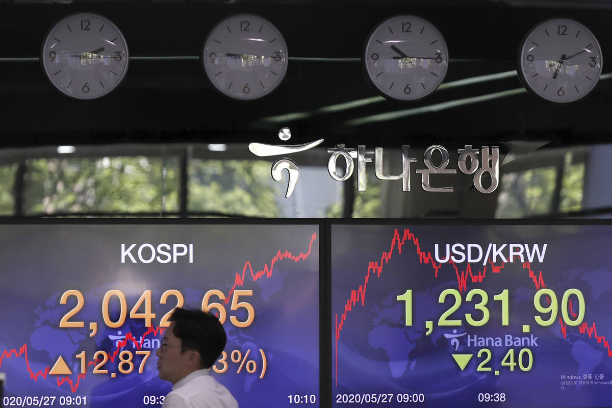 A currency trader walks by the screens showing the Korea Composite Stock Price Index (KOSPI), l ...