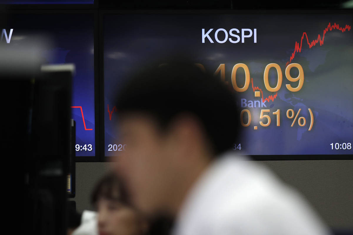 Currency traders watch computer monitors near the screen showing the Korea Composite Stock Pric ...