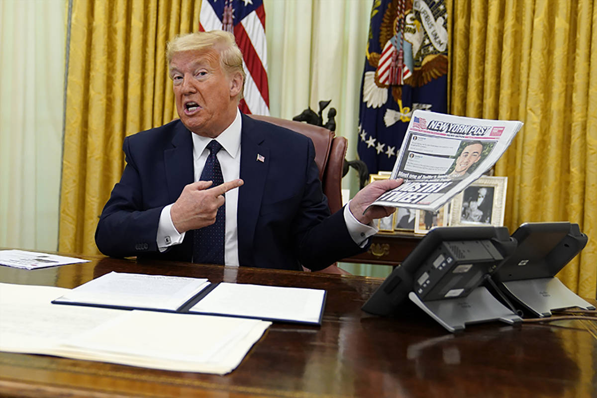 President Donald Trump holds up a copy of the New York Post as speaks before signing an executi ...