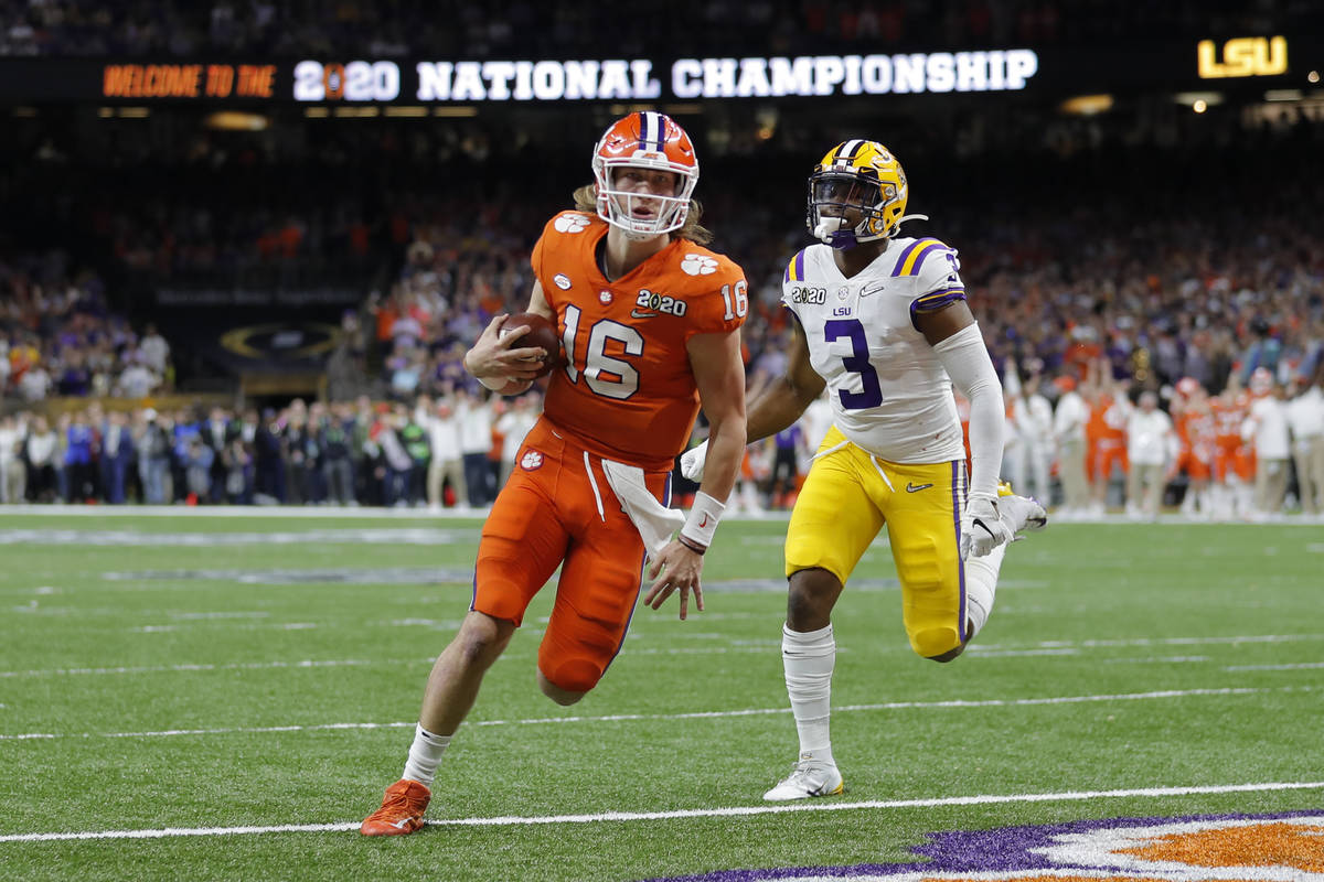 Clemson quarterback Trevor Lawrence scores past LSU safety JaCoby Stevens during the first half ...