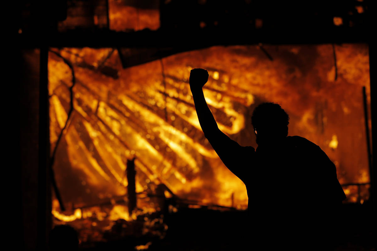 A protester gestures in front of the burning 3rd Precinct building of the Minneapolis Police De ...