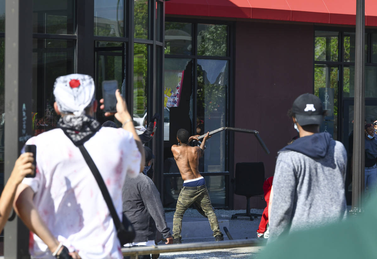 A man breaks a window at the Furniture Barn store on University Avenue West, Thursday, May 28, ...