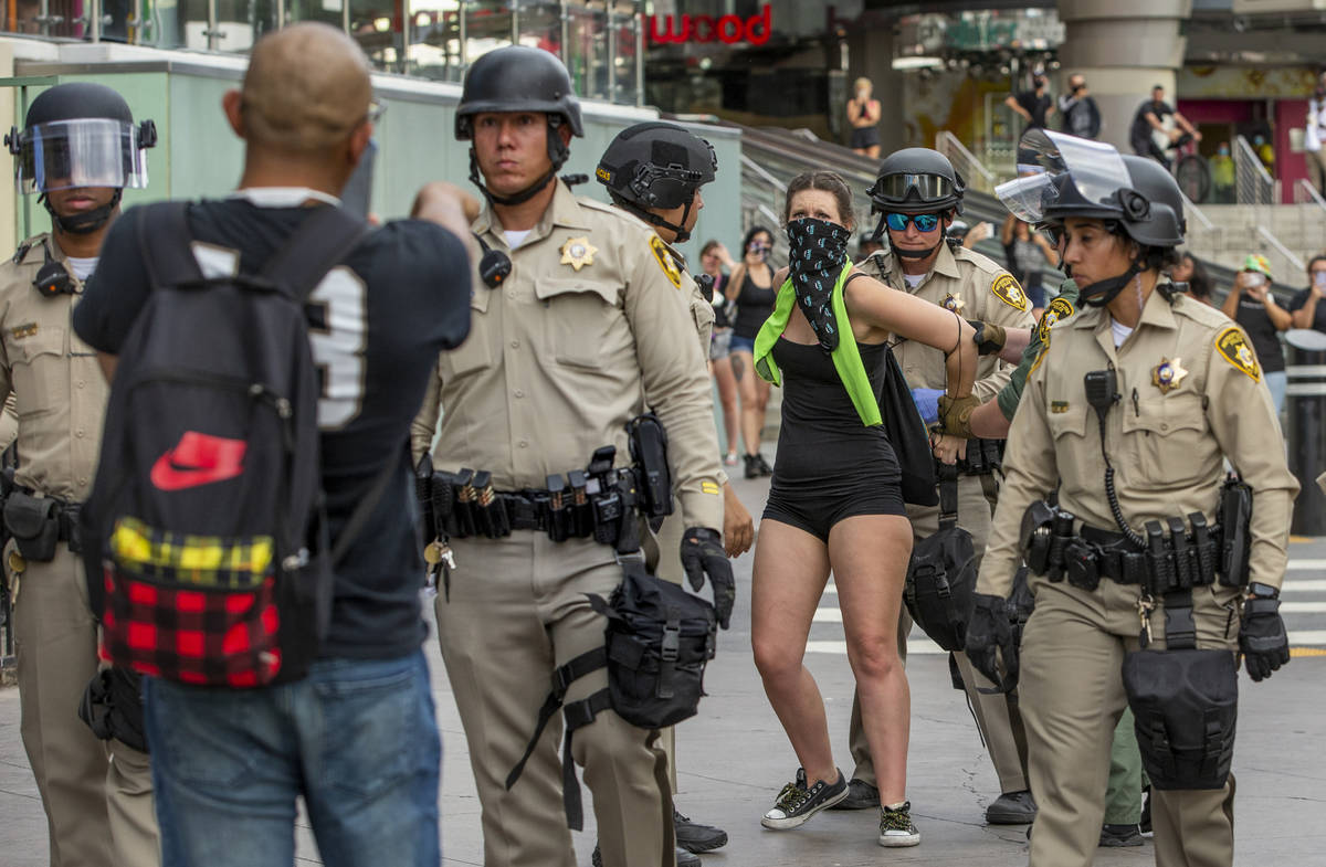 A protestor, right, is arrested as another pleads with Las Vegas Police officers who are lined ...