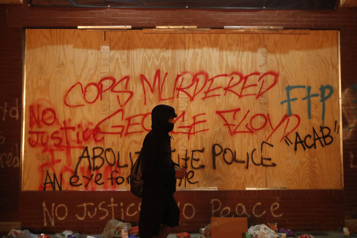 A person walks past a building covered with graffiti Thursday, May 28, 2020, in Minneapolis. Pr ...