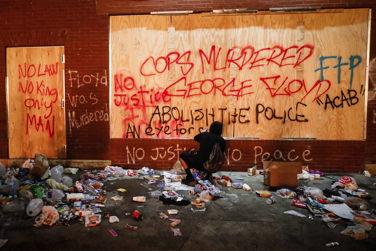 A protestor sprays graffiti on a wall near the Minneapolis 3rd Police Precinct, Thursday, May 2 ...