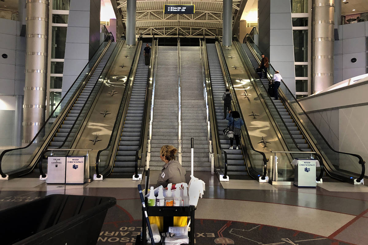 A janitorial employee looks to the few passengers heading through Concourse D in Terminal 3 at ...