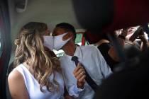 Wearing masks to prevent the spread of the new coronavirus, Thiago do Nascimento, right, and Ke ...