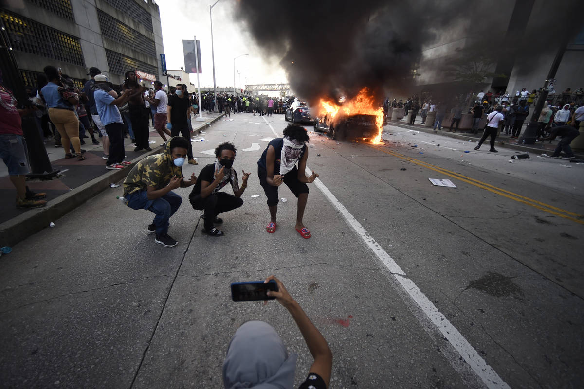 An Atlanta Police Department vehicle burns as people pose for a photo during a demonstration ag ...