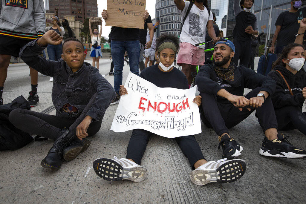 Protesters sit in the street in Los Angeles, Friday, May 29, 2020, in protest over the death of ...