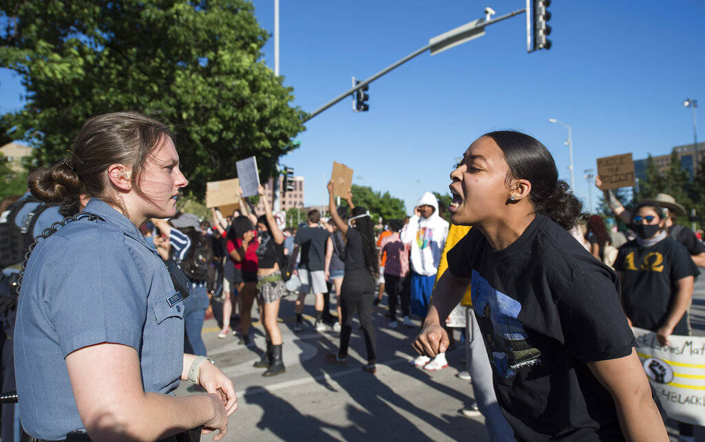 In this May 29, 2020, photo, a police officer stands as a young woman screamed at her during a ...