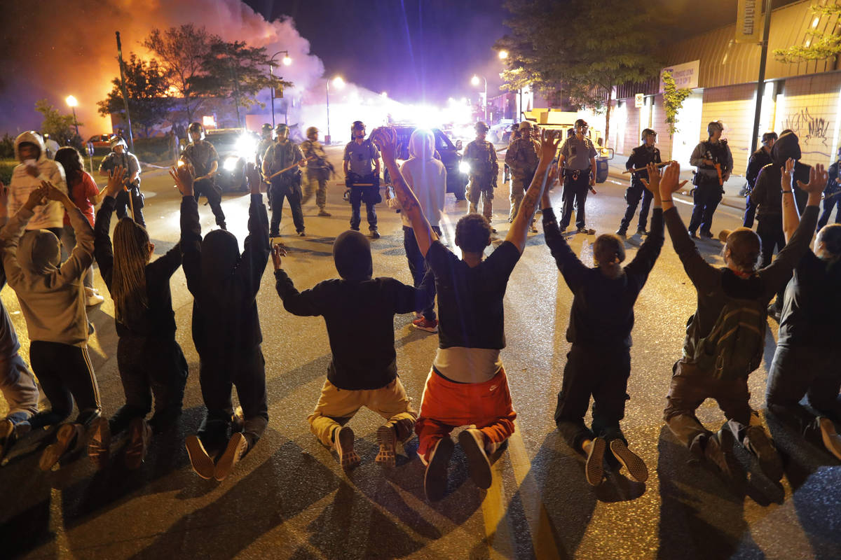 Demonstrators kneel before police Saturday, May 30, 2020, in Minneapolis. Protests continued fo ...