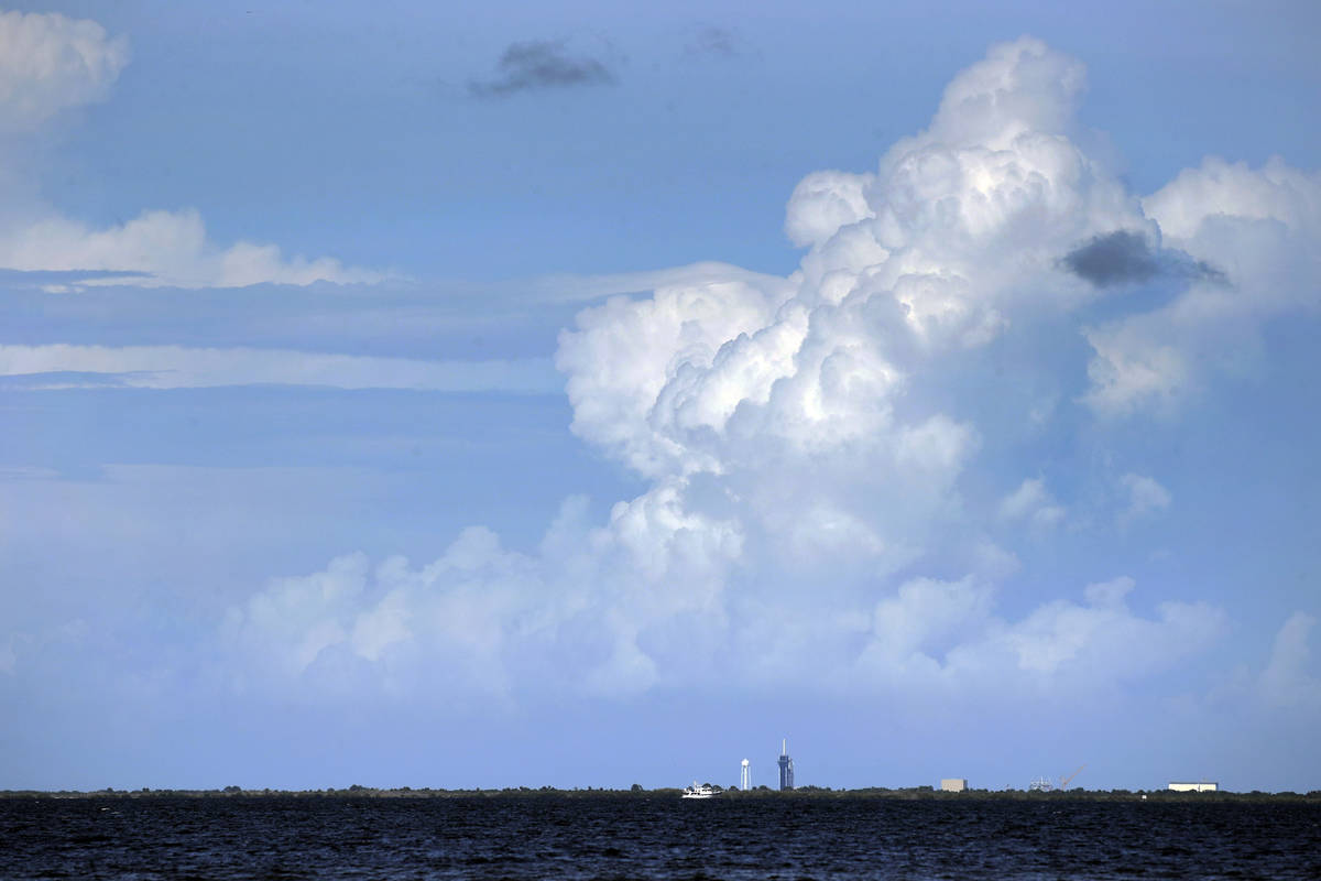The SpaceX Falcon 9, with Dragon crew capsule on top of the rocket, is dwarfed by storm clouds ...