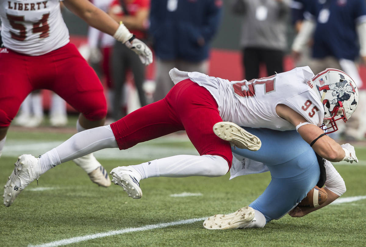 Centennial junior Colton Tenney (10) is leveled in the backfield by Liberty senior defensive en ...