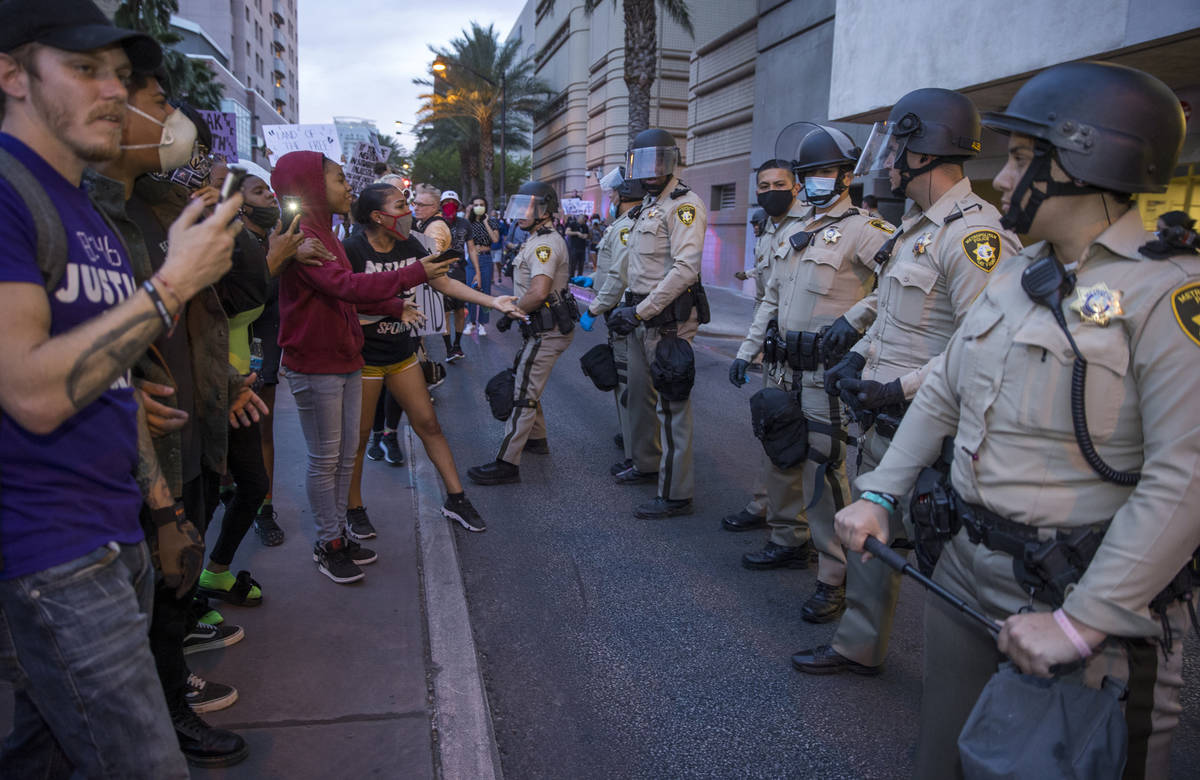 Las Vegas Police look on as protesters confront them while marching along S. Casino Center Driv ...