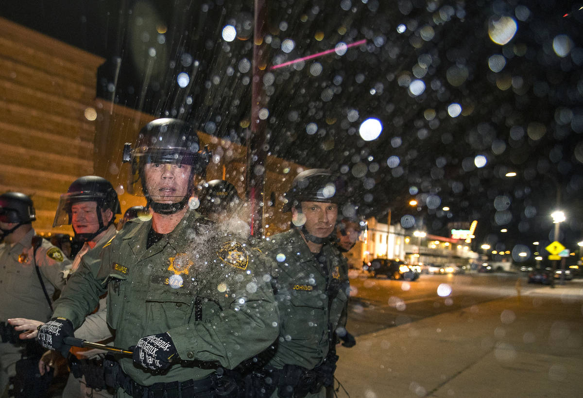 A Las Vegas Police officer is struck on the shoulder by a water bottle during clashes with prot ...