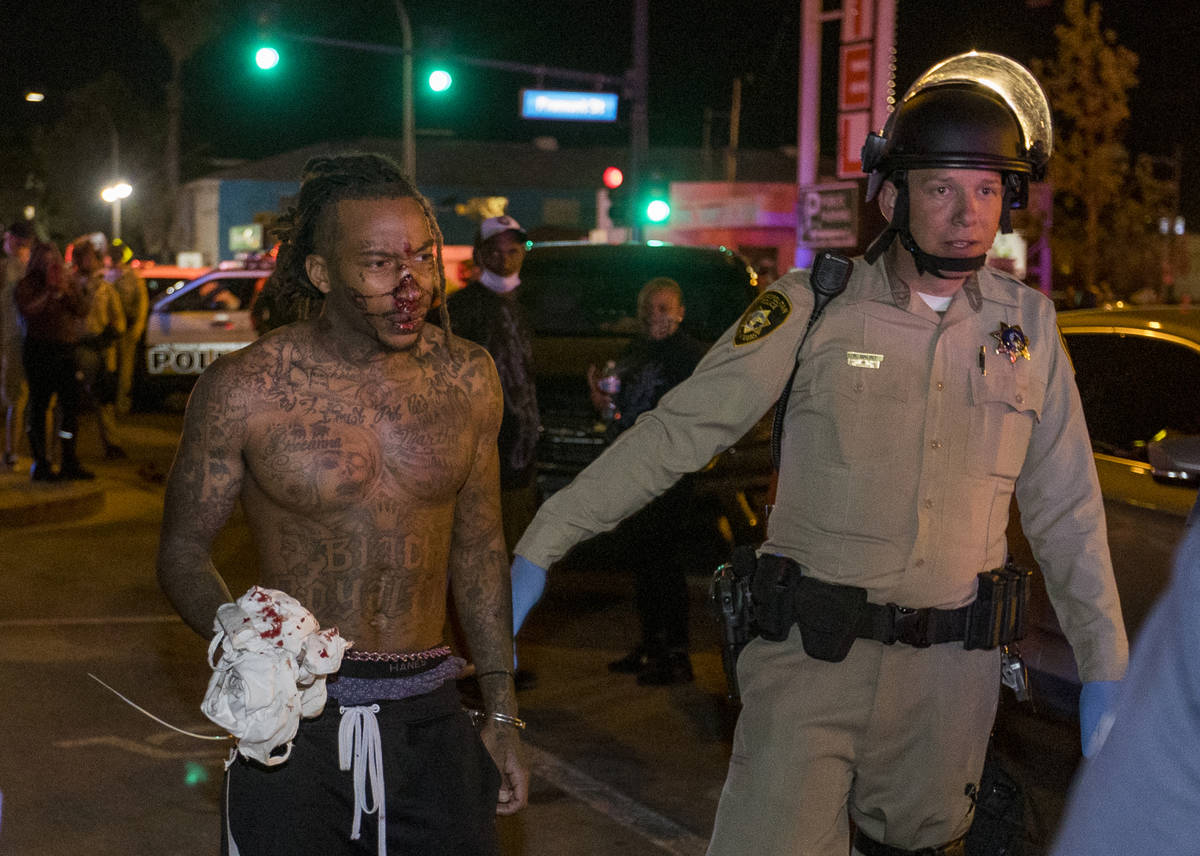 Las Vegas Police officers escort a bloodied protester from a Black Lives Matter march about Con ...