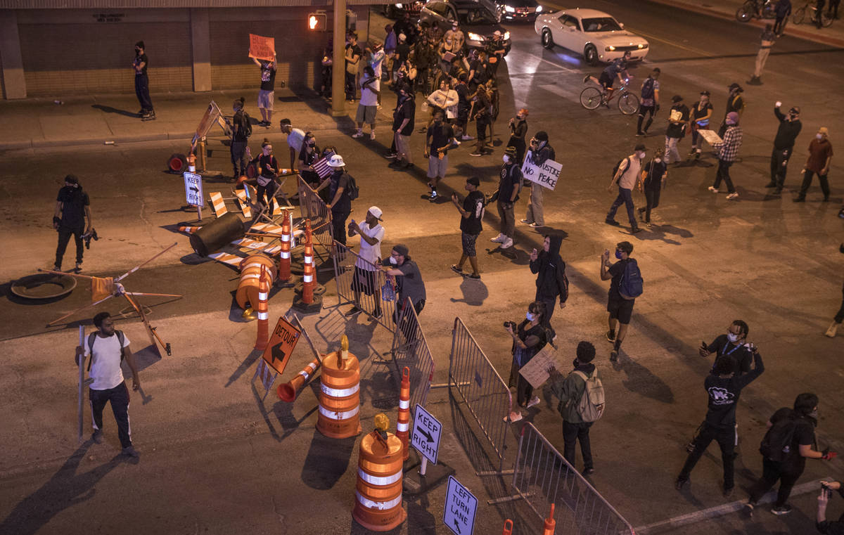 Protesters block the street with signs, barricades and barrels as Las Vegas Police move down La ...