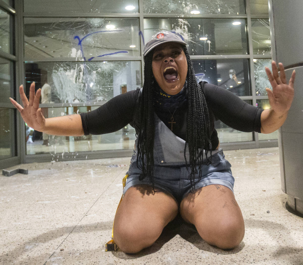 A woman pleads for protesters to stop breaking windows at an office building on South Las Vegas ...