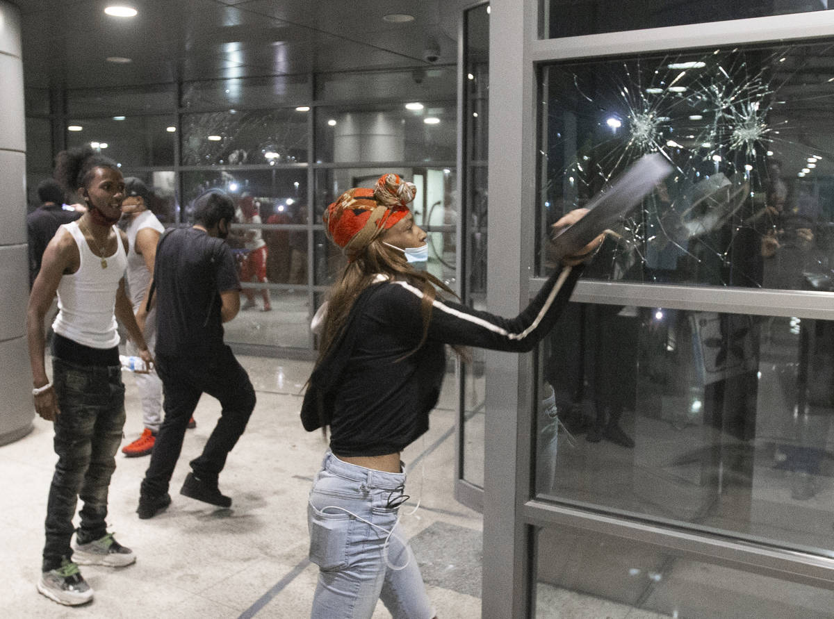 A protester smashes the window of an office building on South Las Vegas Boulevard in downtown L ...