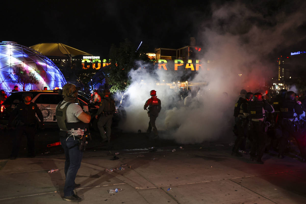Tear gas spreads around police officers as people protest the death of George Floyd in downtown ...