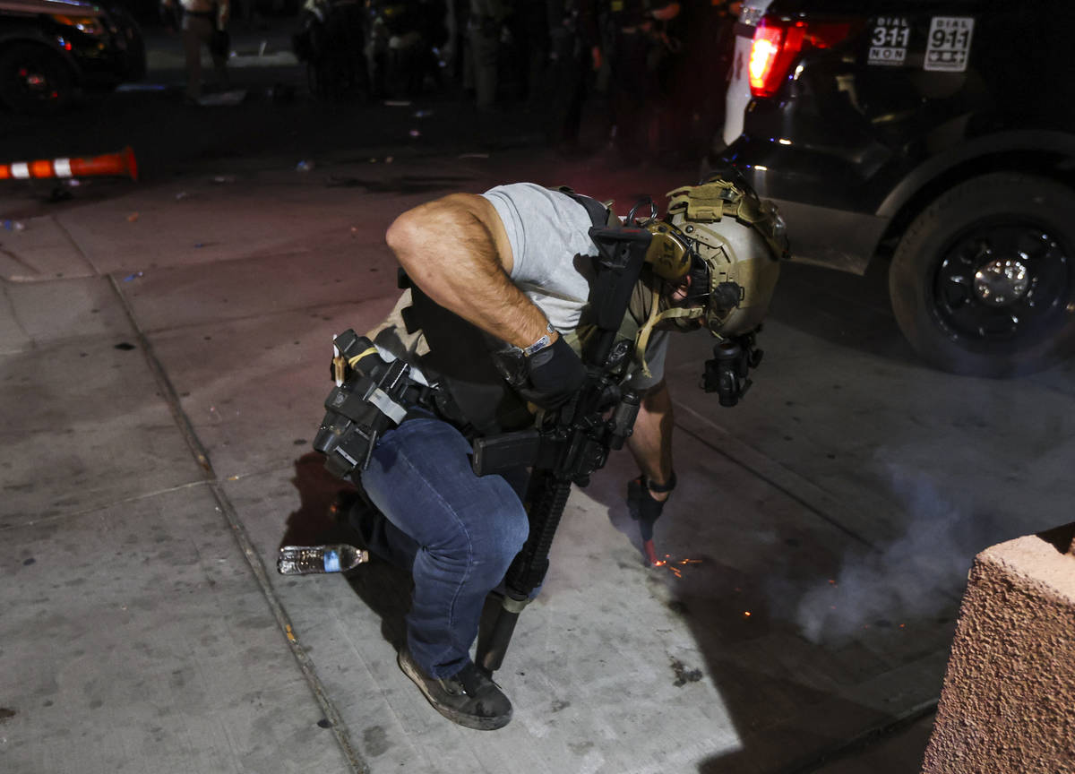 A police officer puts out a firework device that was thrown by a protester in downtown Las Vega ...