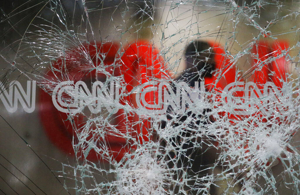A security guard walks behind shattered glass at the CNN building at the CNN Center in the afte ...