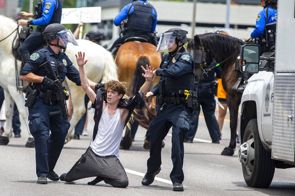 Two Austin Police officers arrest a protester as they shut down southbound Interstate 35 freewa ...