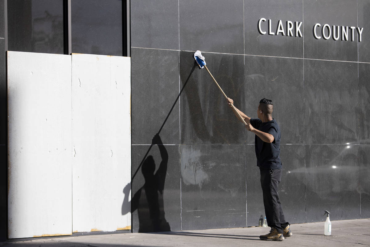 An employee from The D wipes down words written in the dirt on a Clark County building that wer ...