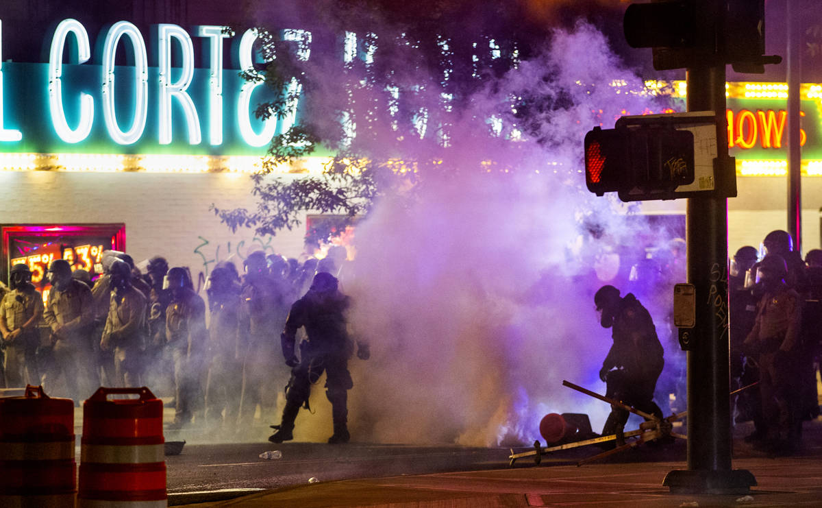 Las Vegas Police are engulfed in tear gas as protesters threw the canisters back on Fremont Str ...