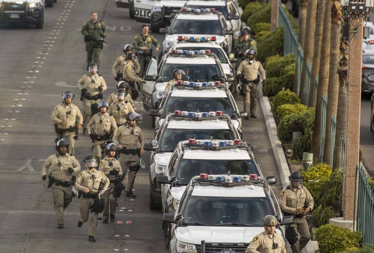 Las Vegas Police officers run to their vehicles during a Black Lives Matter protest along the L ...
