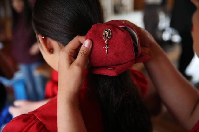 Inside a ranch dining hall, Linsy Enriquez, left, assists Alondra Colon with her ensemble. (Eri ...
