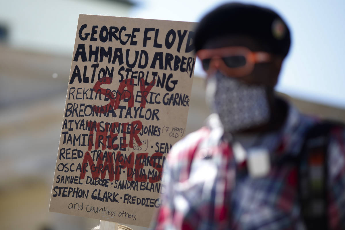 Ismael Kamara stand in front of a poster with names from people died after police violence the ...