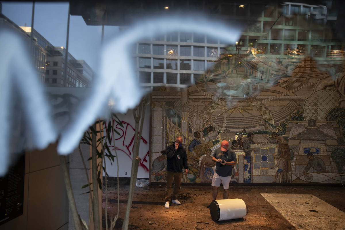 Workers are seen through a shattered window at the AFL-CIO building in Washington, Monday, June ...