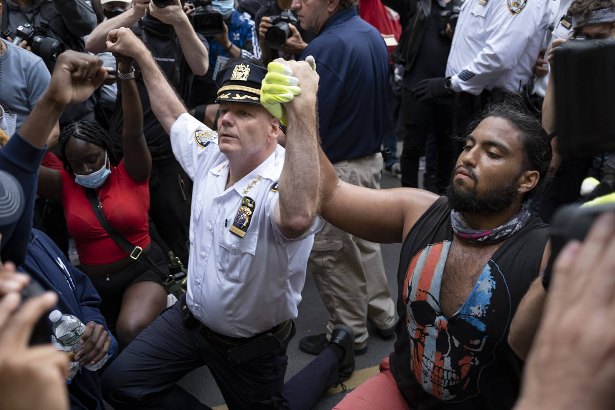 Chief of Department of the New York City Police, Terence Monahan, takes a knee with activists a ...