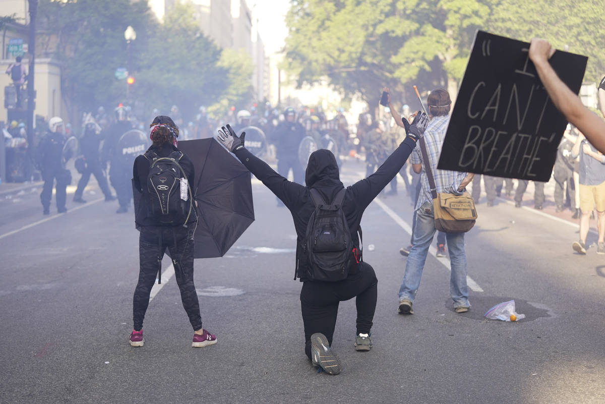 Demonstrators kneel in front of a line of police officers during a protest for the death of Geo ...