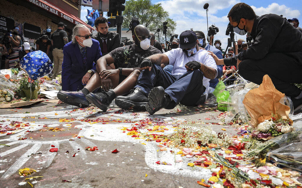 An emotional Terrence Floyd, second from right, is comforted as he sits at the spot at the inte ...