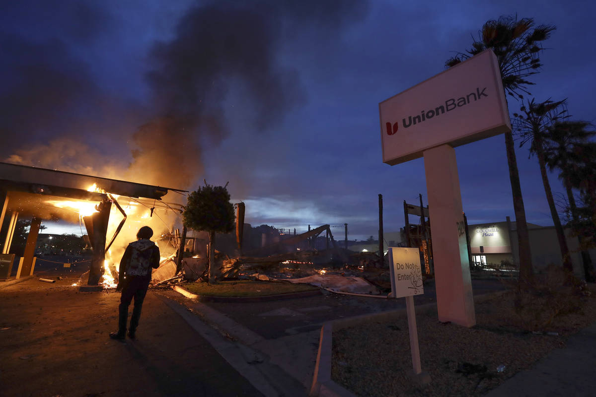 A man looks on as a bank burns after a protest over the death of George Floyd. (AP Photo/Gregor ...