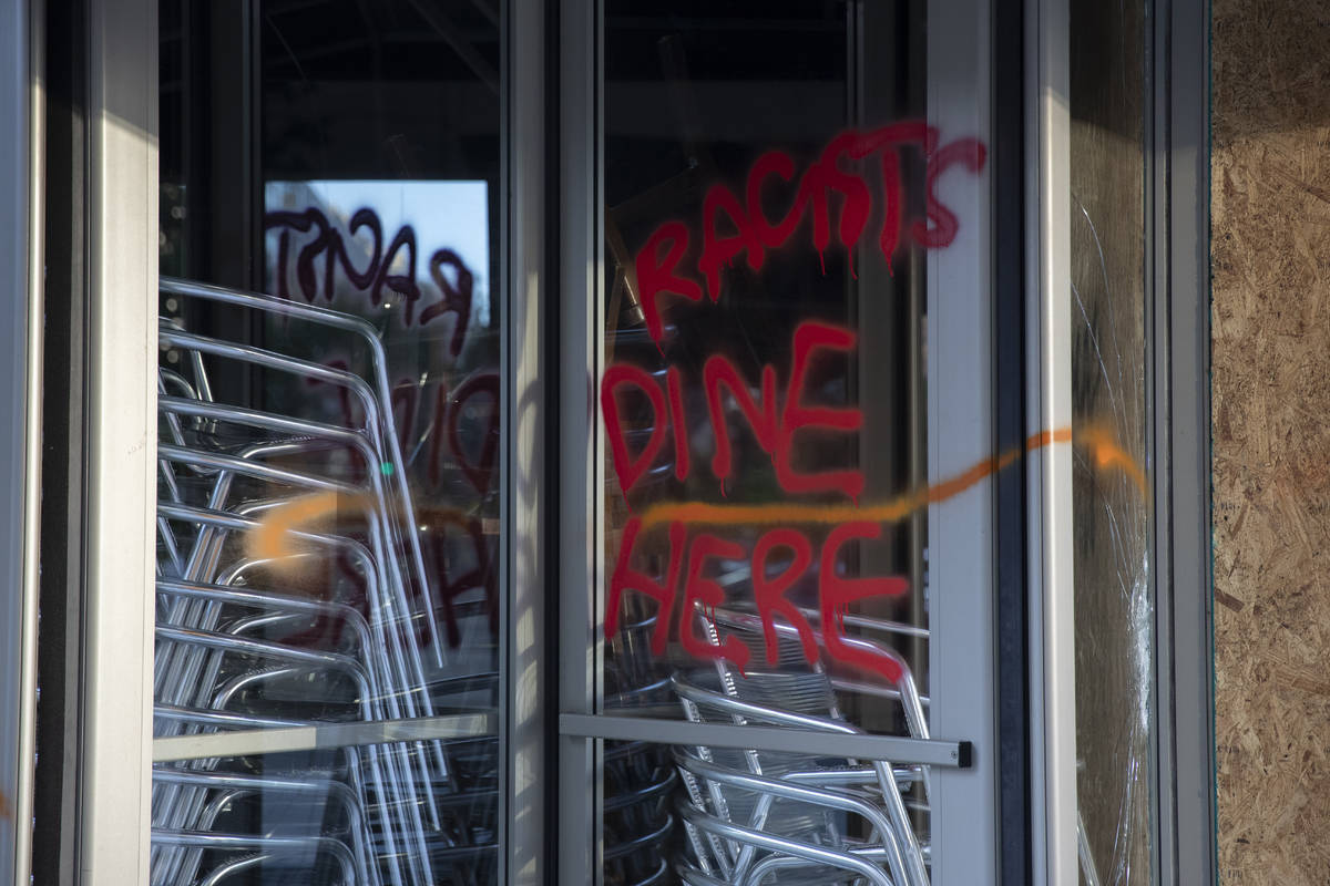 Spray paint the reads "Racists Dine Here" is seen on a revolving door or a restaurant ...