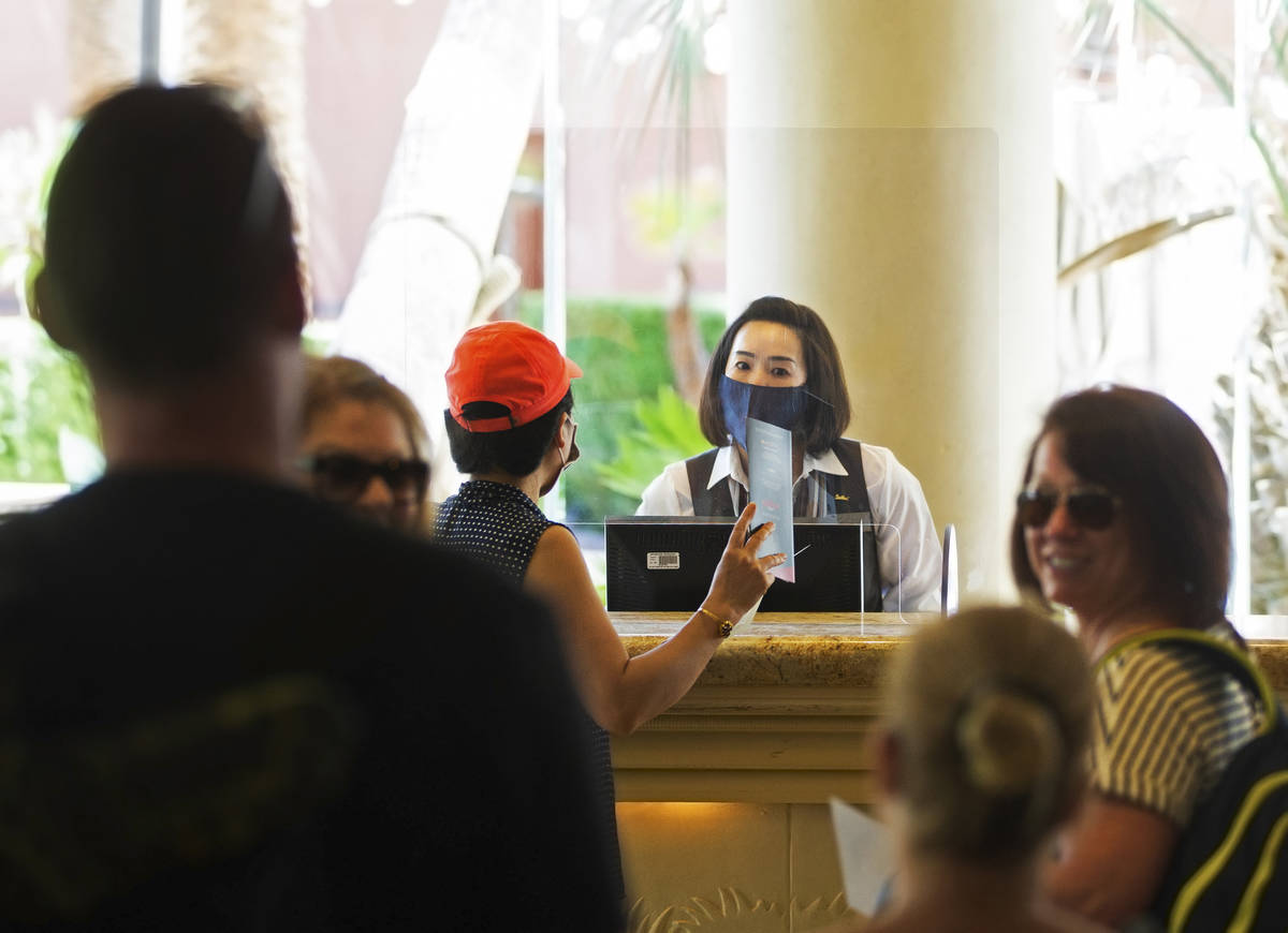 Guest service representatives wear protective masks and gloves while checking people in at TI o ...