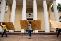 Workers carry large wood boards past the historical St. John's Episcopal Church across Lafayett ...