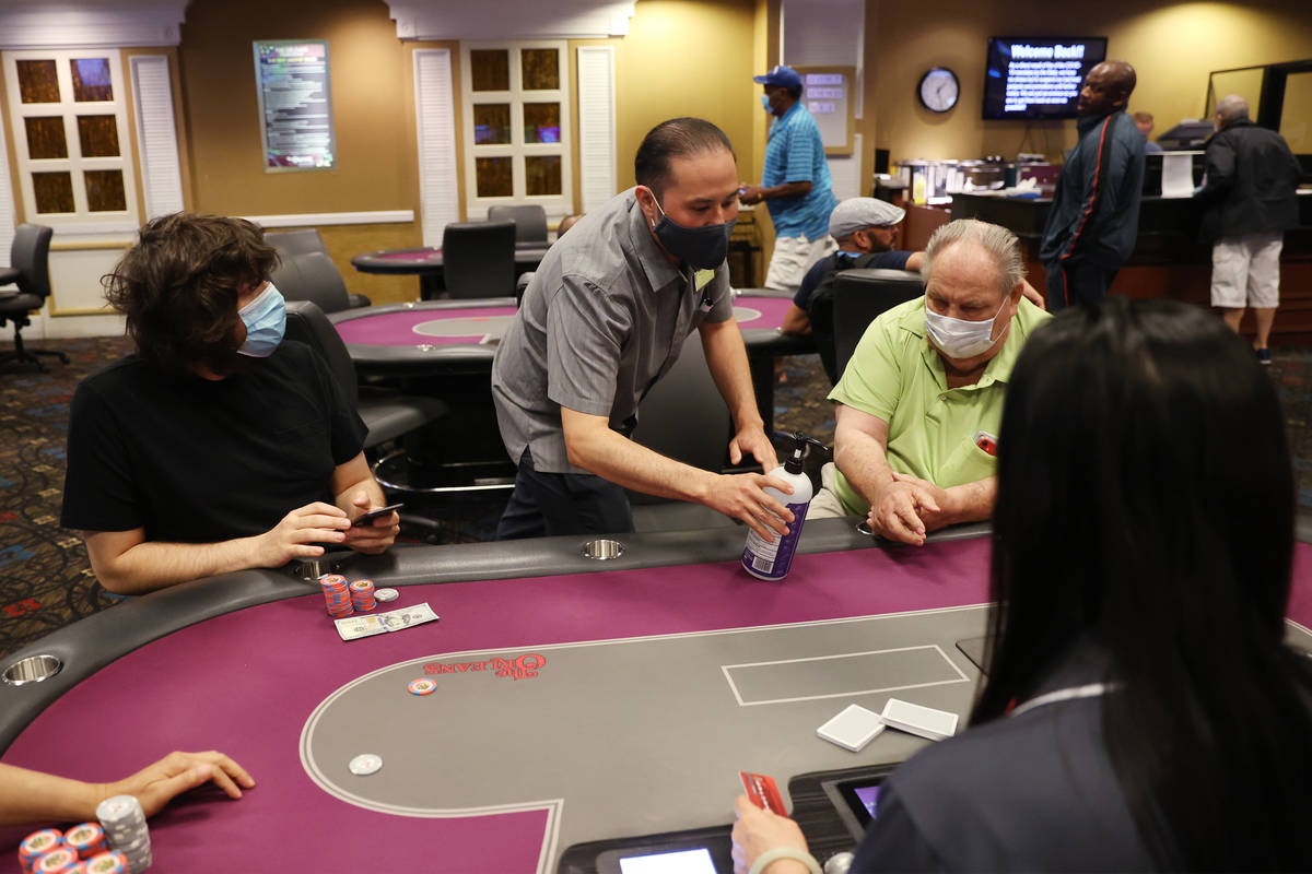 Poker shift manager Kenneth Davis deliver a new bottle of Gand sanitizer to a table in the poke ...