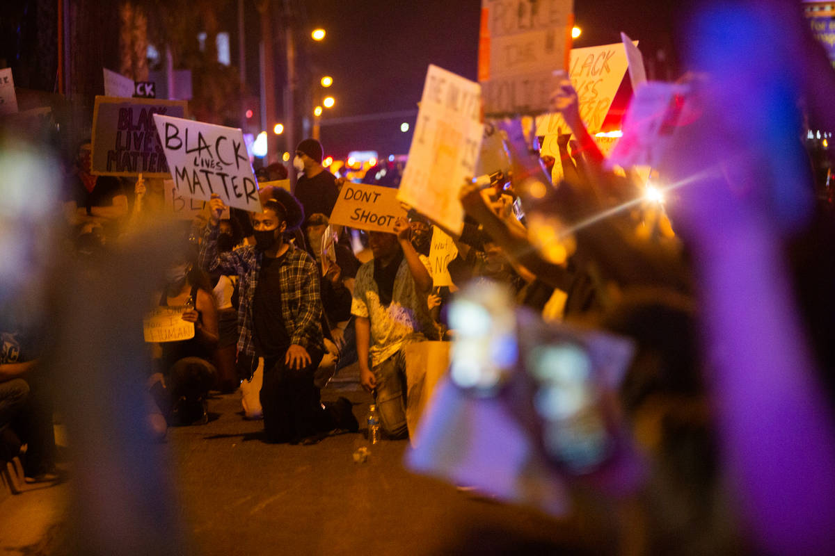 Protesters drop to their knees together before taking a moment of silence during a Black Lives ...