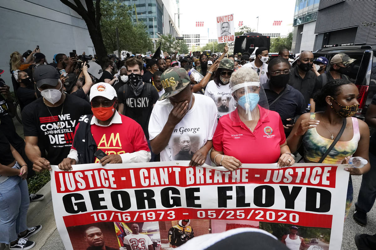 LaTonya Floyd, third from left, participates in a march to protest the death of her brother, Ge ...