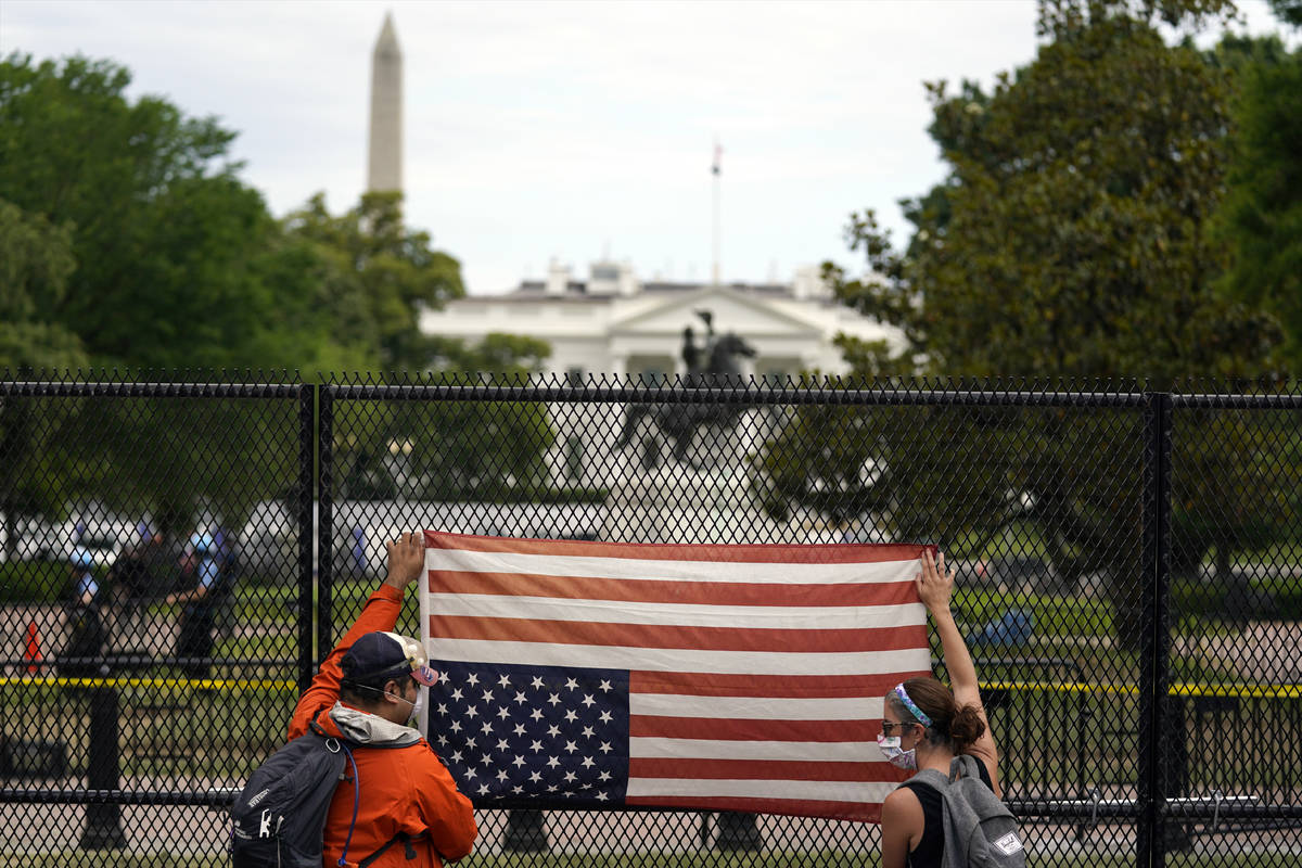 Demonstrators protest the death of George Floyd with an upside-down American flag, Tuesday, Jun ...