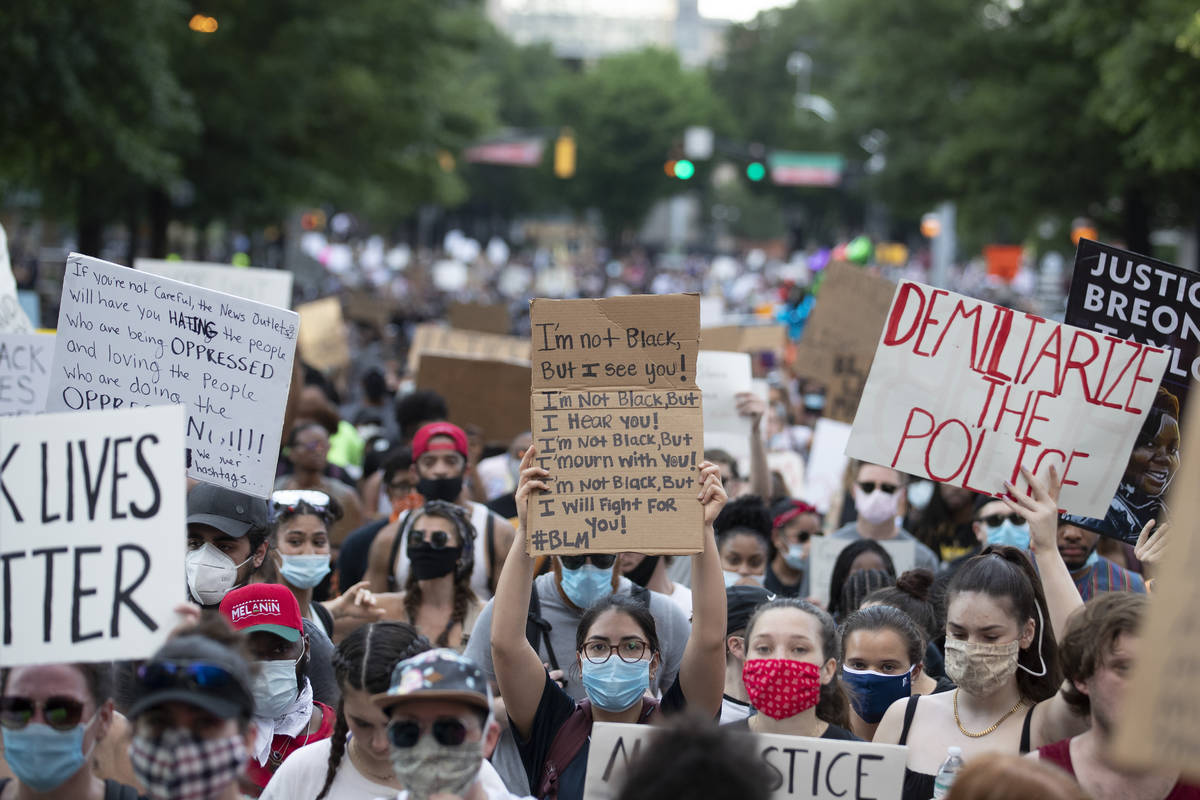 People carry signs as they march Monday, June 1, 2020, in Atlanta during a demonstration over t ...