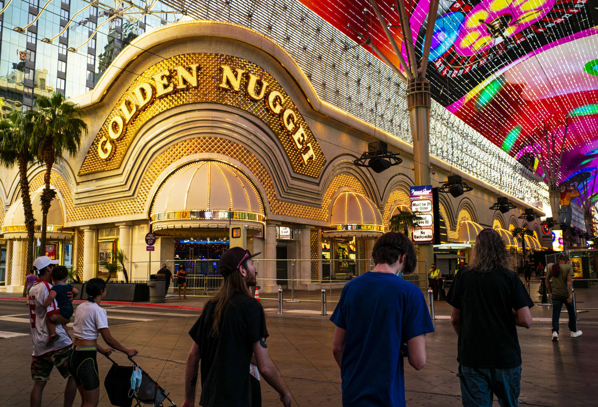 People walk around the Fremont Street Experience as hotel-casinos reopen in downtown Las Vegas ...
