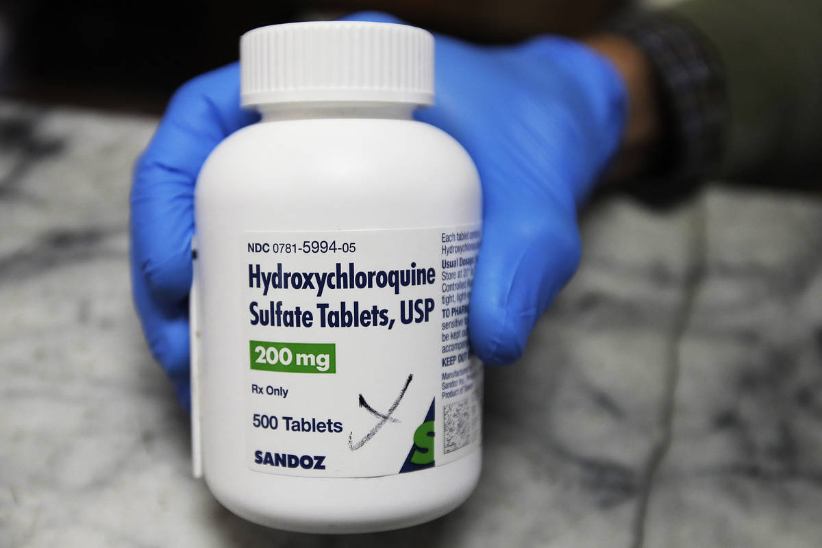 FILE - In this April 6, 2020 file photo, a pharmacist holds a bottle of the drug hydroxychloroq ...