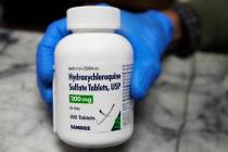 FILE - In this April 6, 2020 file photo, a pharmacist holds a bottle of the drug hydroxychloroq ...